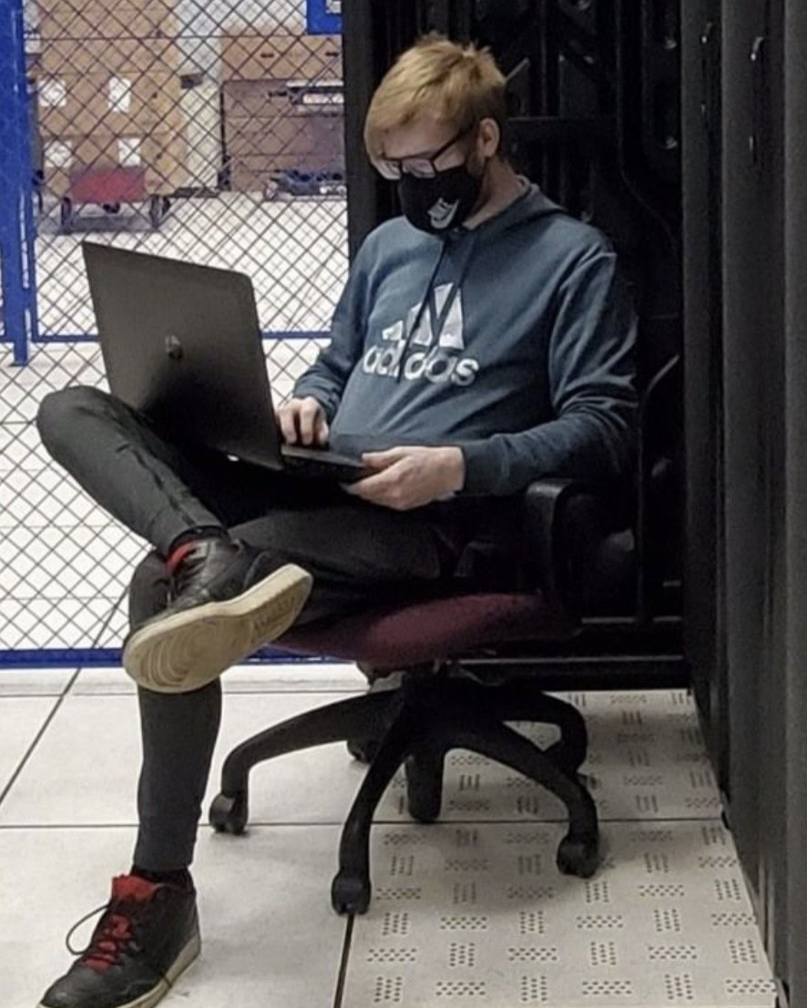 Luke using a laptop beside datacenter racks